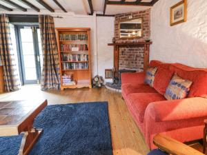 sala de estar con sofá rojo y chimenea en The Corn Store en Corwen
