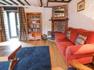 un soggiorno con un divano rosso e un camino di The Corn Store a Corwen