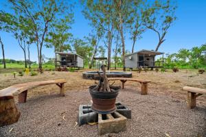 a group of picnic tables and benches in a park at Litchfield Tropical Stay in Batchelor