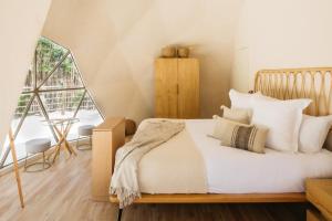 um quarto com uma cama com lençóis brancos e almofadas em Alma Maya Resort em Puerto Morelos