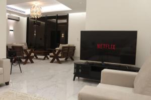 a living room with a flat screen tv and chairs at فيلا عصرية بمدخل خاص و مسبح in Riyadh