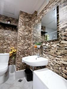 a bathroom with a white sink and a stone wall at Condo Azur Suites A326 Amani Resorts Residences , 5 minutes Airport, Netflix, Stylish, Cozy with Luxurious Swimming Pool in Pusok