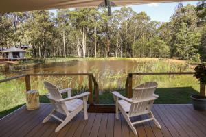 two chairs on a deck with a view of a lake at Two Fat Blokes Moroccan Glamping in Pokolbin