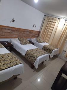 um quarto de hotel com três camas e uma janela em Amaru Hotel em Copiapó