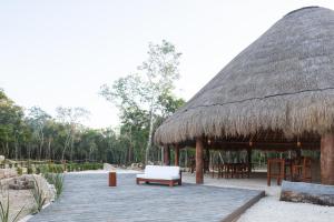 Alma Maya Resort في بويرتو موريلوس: جناح بسقف من القش مع مقاعد وطاولات