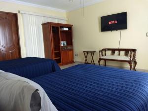 um quarto com uma cama azul e uma televisão em La Casa Bonita de Pueblo Nuevo em El Pueblito