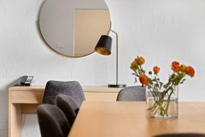 - une salle à manger avec une table, des chaises et un miroir dans l'établissement Oxley Court Serviced Apartments, à Canberra