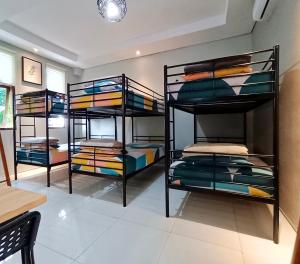 Habitación con 3 literas y mantas coloridas. en Sabi Guest House with Strategic Hostel Styles at Prawirotaman Tourist Area by Sabi House en Yogyakarta