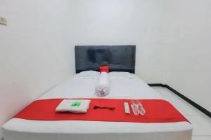 Una cama blanca con toallas rojas y blancas. en RedDoorz at Permana Homestay near Supadio Airport Pontianak, en Limbung