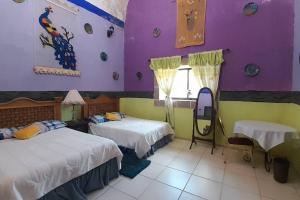 HuichapanにあるHacienda Los Girasoles Siglo XVIIIの紫と緑の壁の客室で、ベッド2台が備わります。