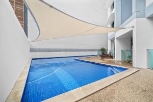 an indoor swimming pool with blue water in a building at Spectacular Darwin apartment in Darwin