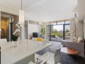 a kitchen and living room with a white table and chairs at 2bdrm Skyline Views - Prime for River, WACA, OPTUS Stadium in Perth