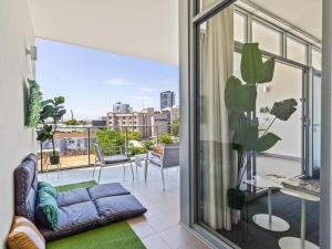 a living room with a couch and a balcony at 2bdrm Skyline Views - Prime for River, WACA, OPTUS Stadium in Perth
