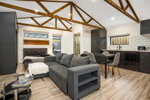 a living room with a gray couch and a kitchen at Studio Unit with Spa Bath in Christchurch