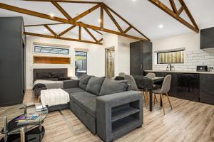 a living room with a gray couch and a kitchen at Studio Unit with Spa Bath in Christchurch