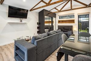 a living room with a large couch and a tv at Studio Unit with Spa Bath in Christchurch
