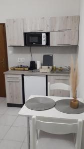 een witte keuken met een tafel en een magnetron bij Főnix Apartmanház in Vonyarcvashegy