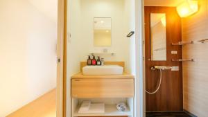 La salle de bains est pourvue d'un lavabo et d'un miroir. dans l'établissement ELE Hotel Kuzuha, à Hirakata