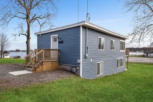uma pequena casa azul com um alpendre e um deque em Lakeside House by Michigan Waterfront Luxury Properties em Montague