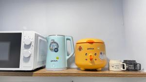 a shelf with a hello kitty mug next to a microwave at Vania House in Ho Chi Minh City