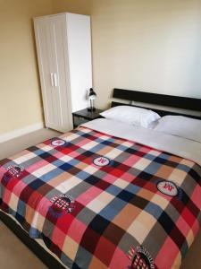 a bedroom with a bed with a plaid blanket on it at Nini Sweet home in Richmond