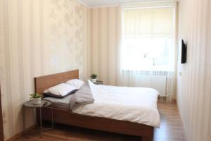 a bedroom with a bed with white sheets and a window at Liepu gatve in Klaipėda