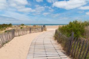 un sentiero in legno attraverso la sabbia su una spiaggia di VILLA DEL RE 3 face à la piscine a La Flotte