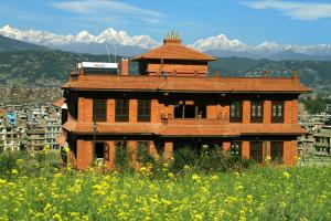 Bhaktapur Paradise Hotel في بهاكتابور: مبنى من الطوب في حقل مع جبال في الخلفية