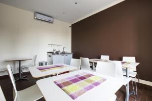 a dining room with white tables and white chairs at Garden Holiday in Marina di Melilli