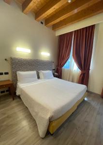 sypialnia z dużym łóżkiem i oknem w obiekcie Green Park Hotel w mieście Peschiera del Garda