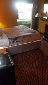 a bed in a hotel room with avertisement at OSU 2 Queens Hotel Room 107 Hot Tub Booking in Stillwater