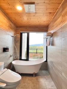 ein Bad mit einer Badewanne, einem WC und einem Fenster in der Unterkunft 如沐咖啡旅宿 in Xingjian