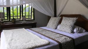 a bedroom with a bed with pillows and a window at VILLA BAMBOO in Silebeng