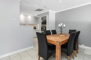 a dining room with a wooden table and black chairs at Blackwood Stays in Spearwood