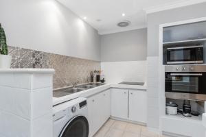 a white kitchen with a washer and dryer at Blackwood Stays in Spearwood