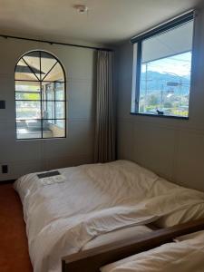 łóżko w pokoju z dużym oknem w obiekcie KIIIYA cafe&hostel w mieście Azumino