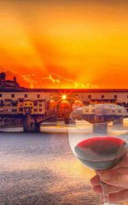 a hand holding a wine glass in front of a bridge at La Luna Guest House in Florence