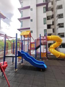 un parque infantil con un tobogán frente a un edificio en Cozy Condo at Melaka Top Hill, 7-9pax en Ayer Keroh