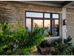 une fenêtre d'une maison avec vue sur le coucher du soleil dans l'établissement Hotel Sunnyside Palace, Almora, à Almora