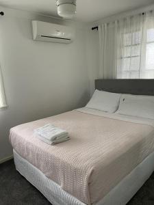 a white bedroom with a bed with two towels on it at Todd Street 72 in Townsville
