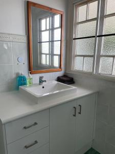 ein weißes Badezimmer mit einem Waschbecken und einem Spiegel in der Unterkunft Todd Street 72 in Townsville