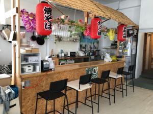 ein Restaurant mit einer Bar mit Stühlen und roten Laternen in der Unterkunft POSSE宮古島and宮古島ウエストレンタカー Wi-Fi完備 in Miyako-jima