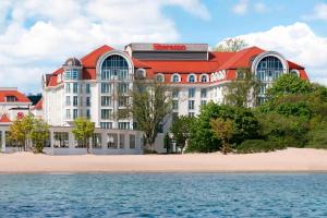 a building with a red roof next to the water at Sheraton Sopot Hotel in Sopot
