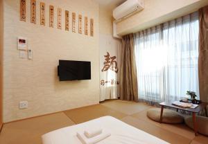 a room with a tv and a bed and a table at V の Boutique House in Osaka