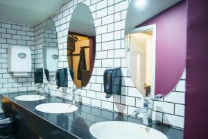 a bathroom with three sinks and two mirrors at Cinema Capsules in Jerusalem
