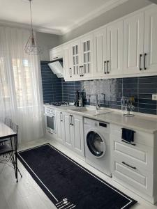 uma cozinha com armários brancos e uma máquina de lavar roupa em Foça- Phokai Living. em Foça