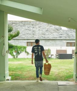 un hombre caminando por un porche con una cesta en Casa Montse. Apartamentos turísticos, en Ribadeo