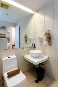 ein Badezimmer mit einem WC, einem Waschbecken und einem Spiegel in der Unterkunft Regency Grand Suites in Manila