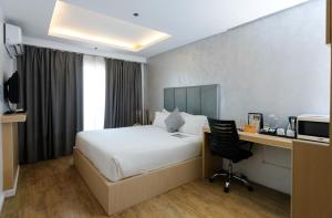a hotel room with a bed and a desk with a computer at Regency Grand Suites in Manila