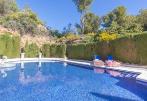 a swimming pool with two blue chairs in a yard at Pool Villa Rancho Domingo family friendly - Happy Rentals in Benalmádena